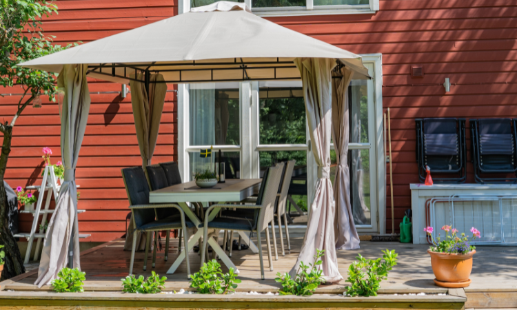 pawilon ogrodowy z zestawem mebli ogrodowych na tarasie przed domem 
