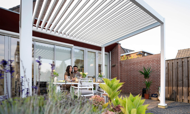 biała pergola ogrodowa z meblami i wypoczywająca parą na tarasie 