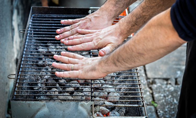 meżczyźni sprawdzający dłońmi temperaturę grilla