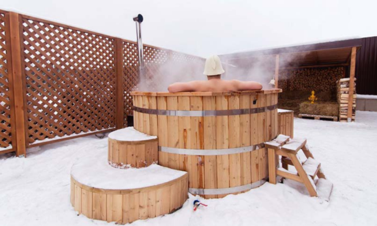 meżczyzna zażywającay terapii gorąca wodą w we własnej prywtanej balii ogrodowej 