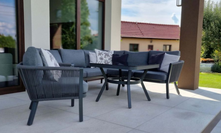 antracytowy narożnik ogrodowy z fotelem i stolikiem ustawiony na tarasie przed domem