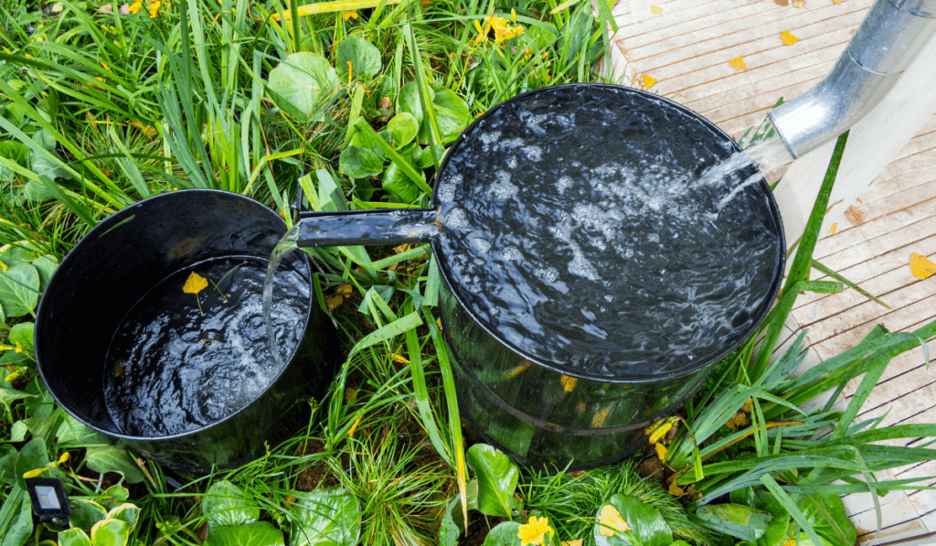 Woda przelewająca się z rynny do czarnej instalacji beczkowej