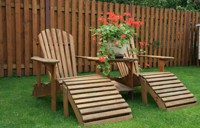 drewniane leżaki/fotele ustawione w ogrodzie na zielonej trawie 