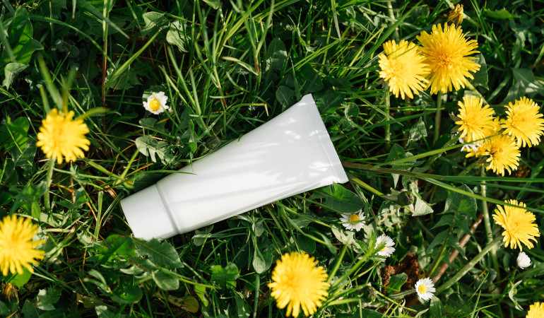 Biała tubka na zielonej trawie i kwiatach