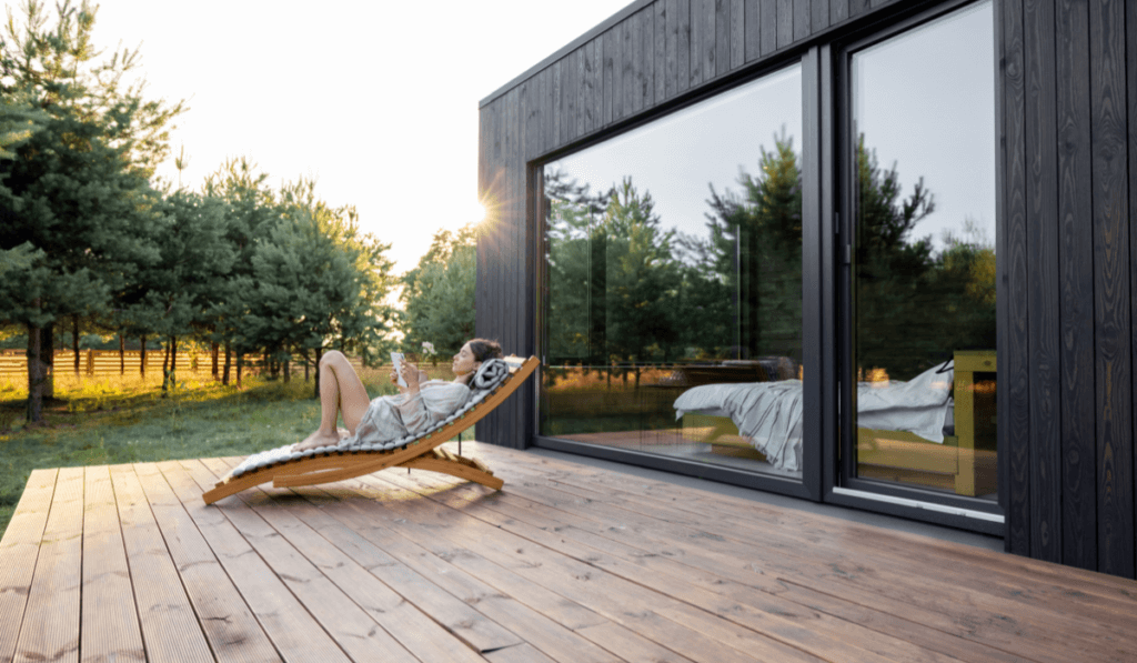 Kobieta leżąca na tarasie przed domem korzystając z tableta