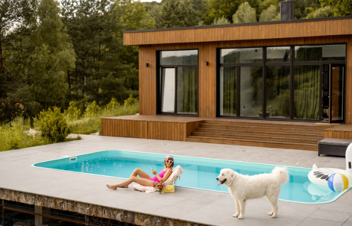 kobieta wypoczywająca nad basenem w domku letniskowym w lesie 