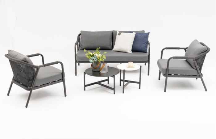 aluminiowe eleganckie meble ogrodowe w szarym kolorze z niskim stolikiem kawowym i szarymi poduszkami na oparciach i siedziskach 