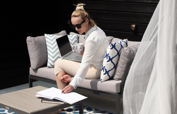 kobieta pracująca na balkonie z laptopem na kolanach w ciepły wiosenny dzień 