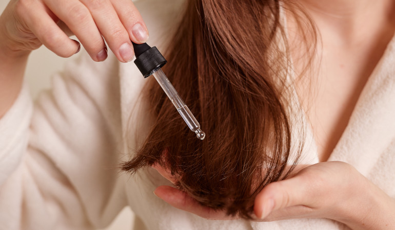 Kobieta aplikuje serum na końcówkach włosów