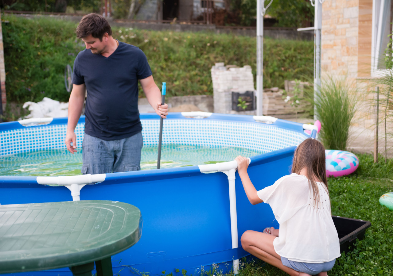 Małżeństwo sprząta basen rozporowy w ogrodzie 
