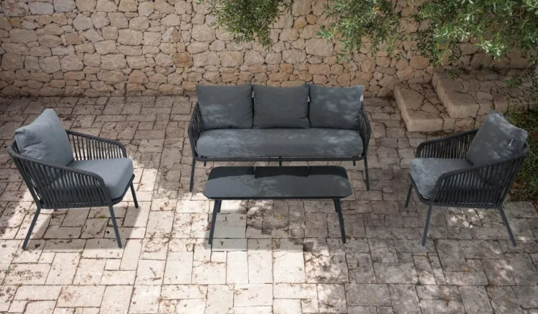 Dwa fotele oraz kanapa ANDERS CAFFE w kolorze szarym na ceglanym tle wraz z czarnym stolikiem 