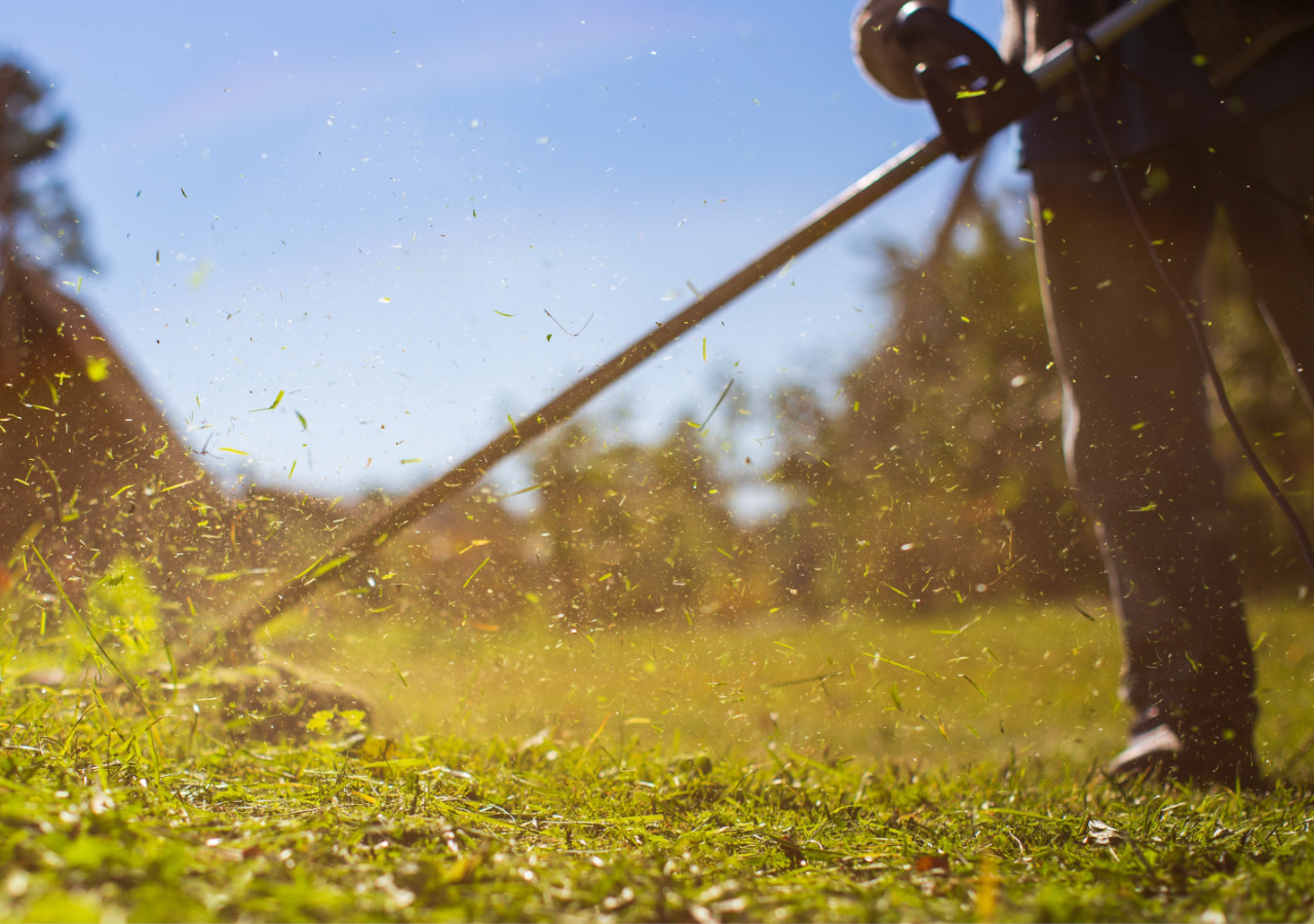 Mężczyzna kosi trawę w pełnym słońcu