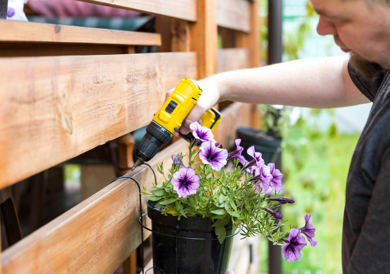 Mężczyzna montuje donicę na płocie