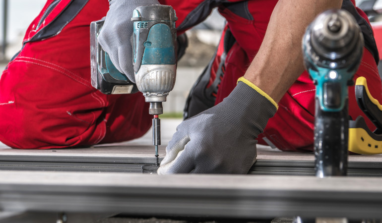 Mężczyzna podczas montażu desek kompozytowych korzystający z wiertarki 