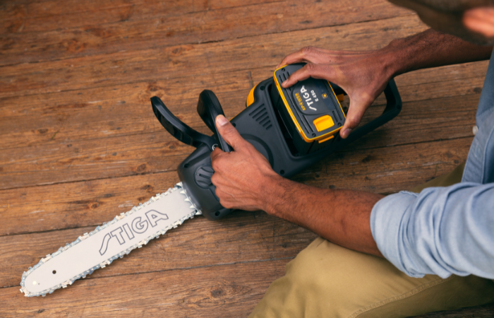 meżczyzna zakładający akumulator do pilarki ogrodowej