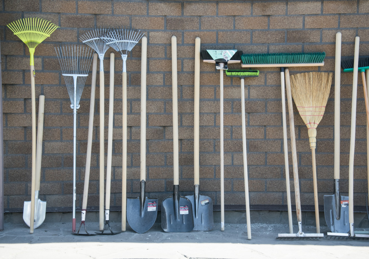 Narzędzia ogrodowe oparte trzonami o cegląną ścianę