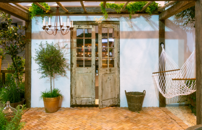 hamak na tarasie z ceglaną podłogą i kamienistym podłożem pod cieniem w ogrodzie w śr&oacute;dziemnomorskim stylu