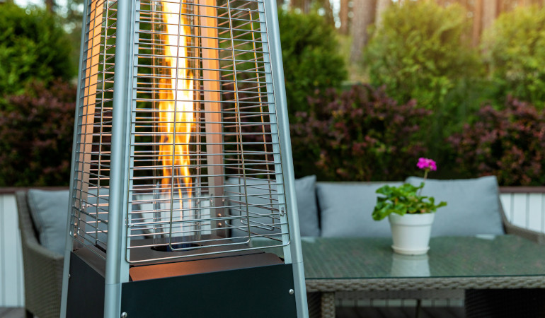 Ogrzewacz ogrodowy na tarasie w otoczeniu zieleni i mebli ogrodowych