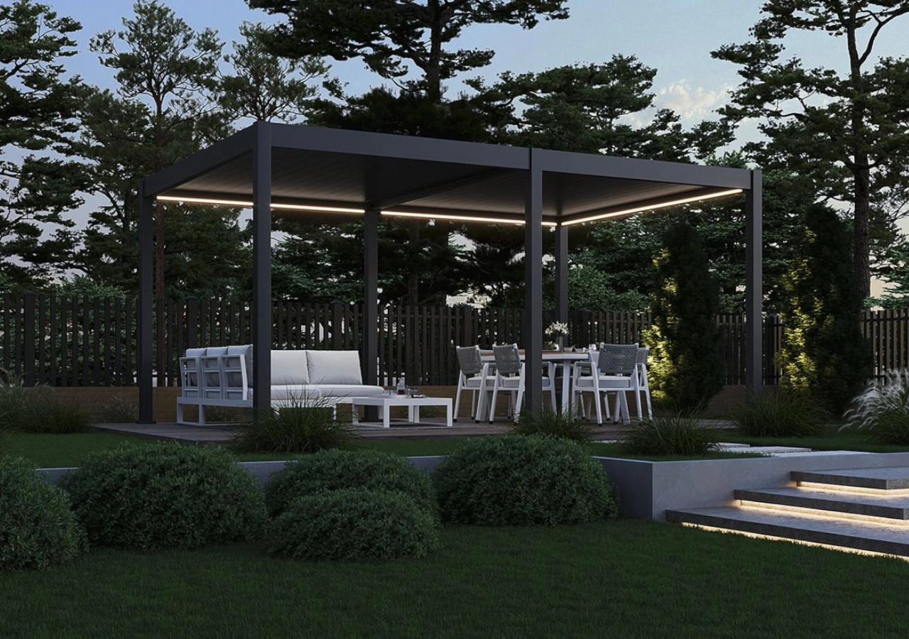 Nowoczesna altana ogrodowa z oświetleniem LED, wyposażona w białe meble wypoczynkowe i st&oacute;ł jadalniany, otoczona zielenią i trawnikiem.