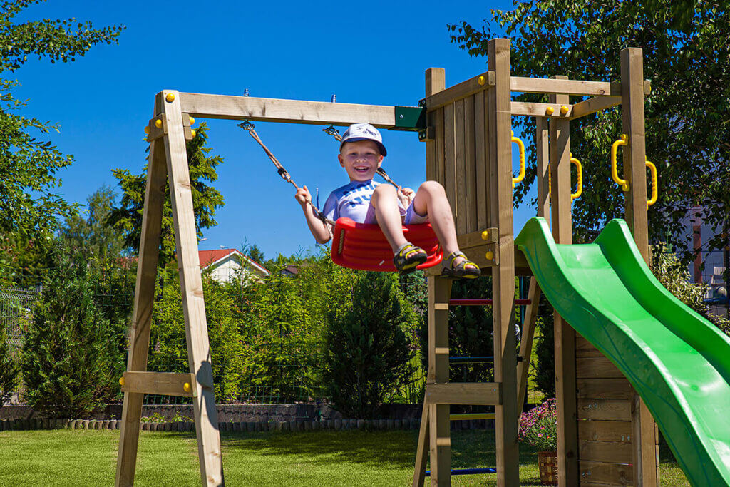 Chłopczyk korzystający z czerwonej huśtawki 