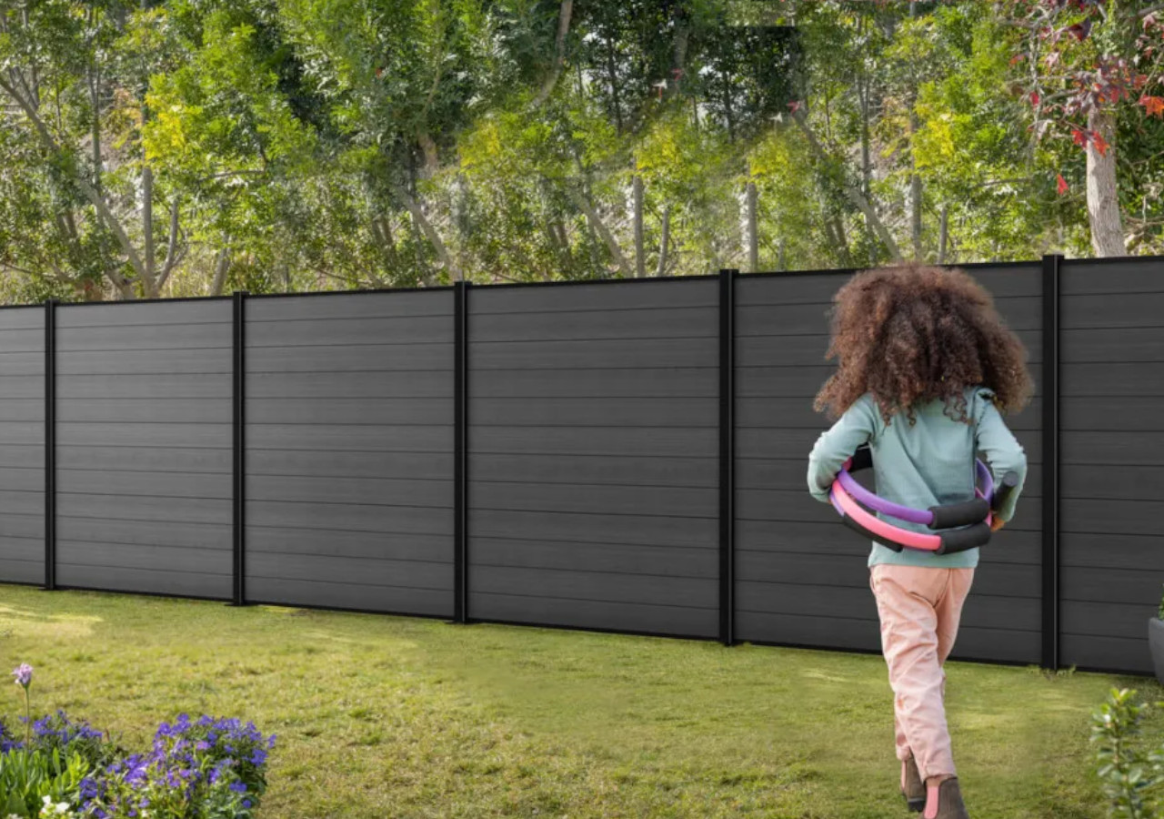 Dziecko idzie w stronę szarego ogrodzenia w ogrodzie 