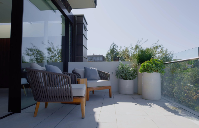 balkon wyłozony szarymi płytkami z pięknymi szarymi meblami ze sznura nylonowego i drewnianym wykończeniem