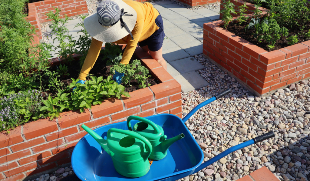 Kobieta w kapeluszu pieli w donicy cementowej