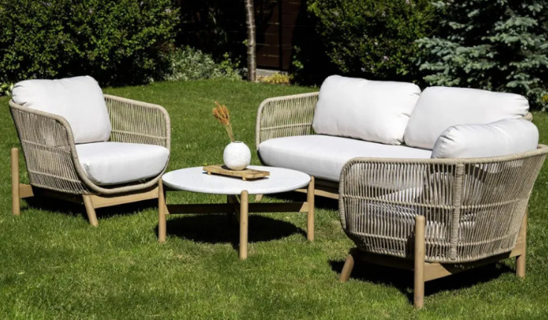 Meble tarasowe ANKARA od Furrore w ogrodowej aranżacji. Dwa białe fotele z naturalnym wykończeniem oraz stolik z białym blatem i ozdobą