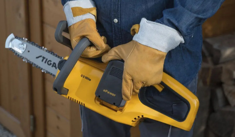 Mężczyzna trzyma w w dłoniach obleconych rękawiczkami ż&oacute;łtymi - pilarkę akumulatorową CS 100E 2.0Ah, seria 100 od Stiga