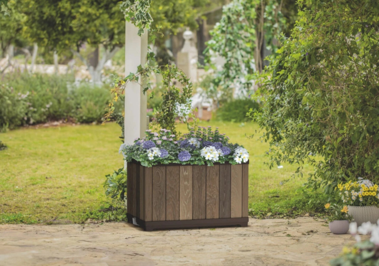 Prostokątna donica ogrodowa z kwiatami na tle zieleni