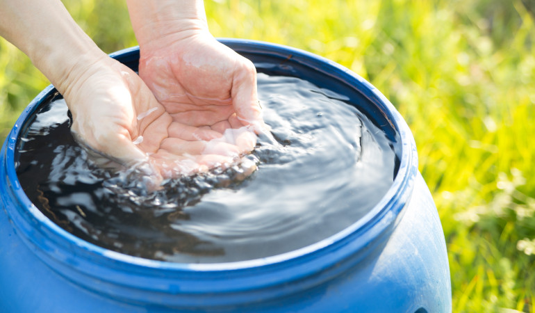 Ręce zanurzone w beczce z deszcz&oacute;wką