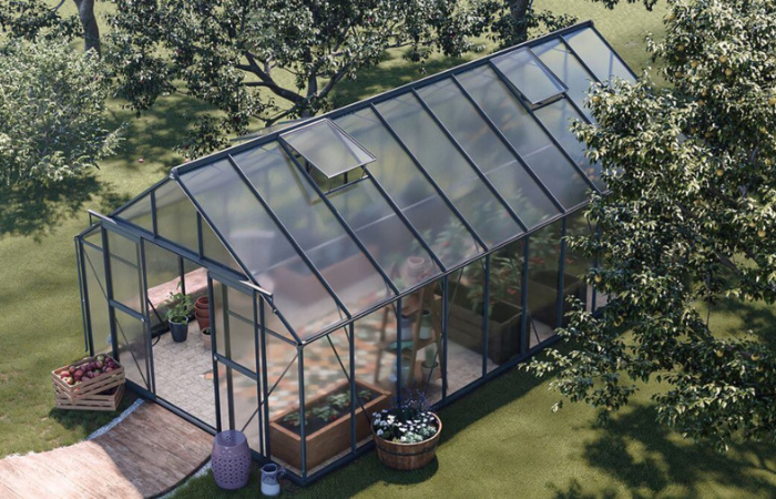 szklarnioa ogrodowa ustawiona w dużym ogrodzie obok domu jednorodzinnego 