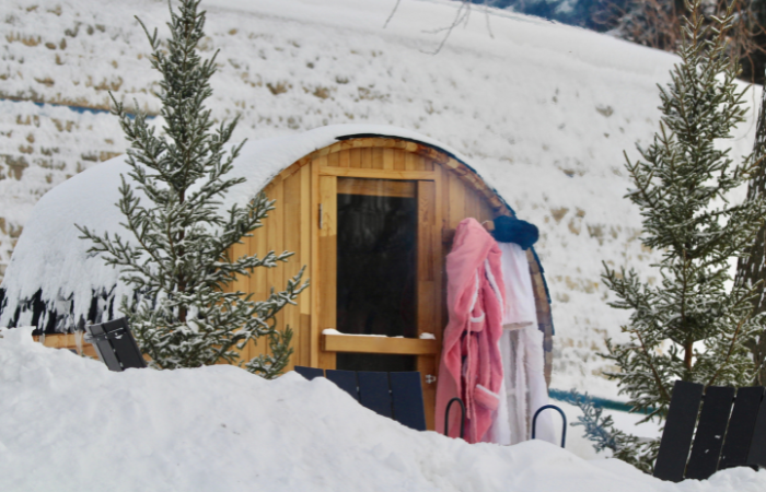   Pokryta śniegiem sauna beczkowa ze szlafrokami