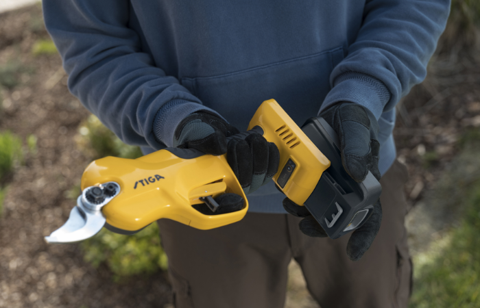 meżczyzna zakładający akumulator do sekatora ogrodowego