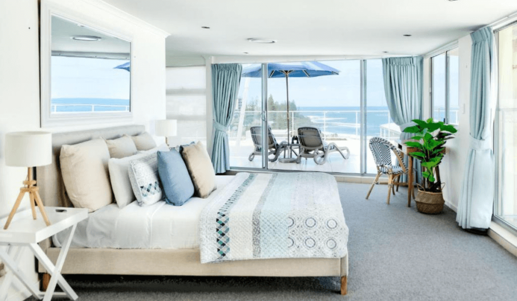 Niebieska sypialnia z wielkim ł&oacute;żkiem małżeńskim, balkonem oraz pojedynczymi elementami dekoracyjnymi