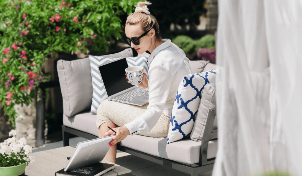 Kobieta siedzi na kanapie wraz z laptopem umiejscowionej na tarasie