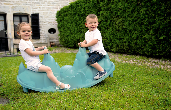dzieci bawiace bujające się w ogrodzie przed domem na bujaczku smoby